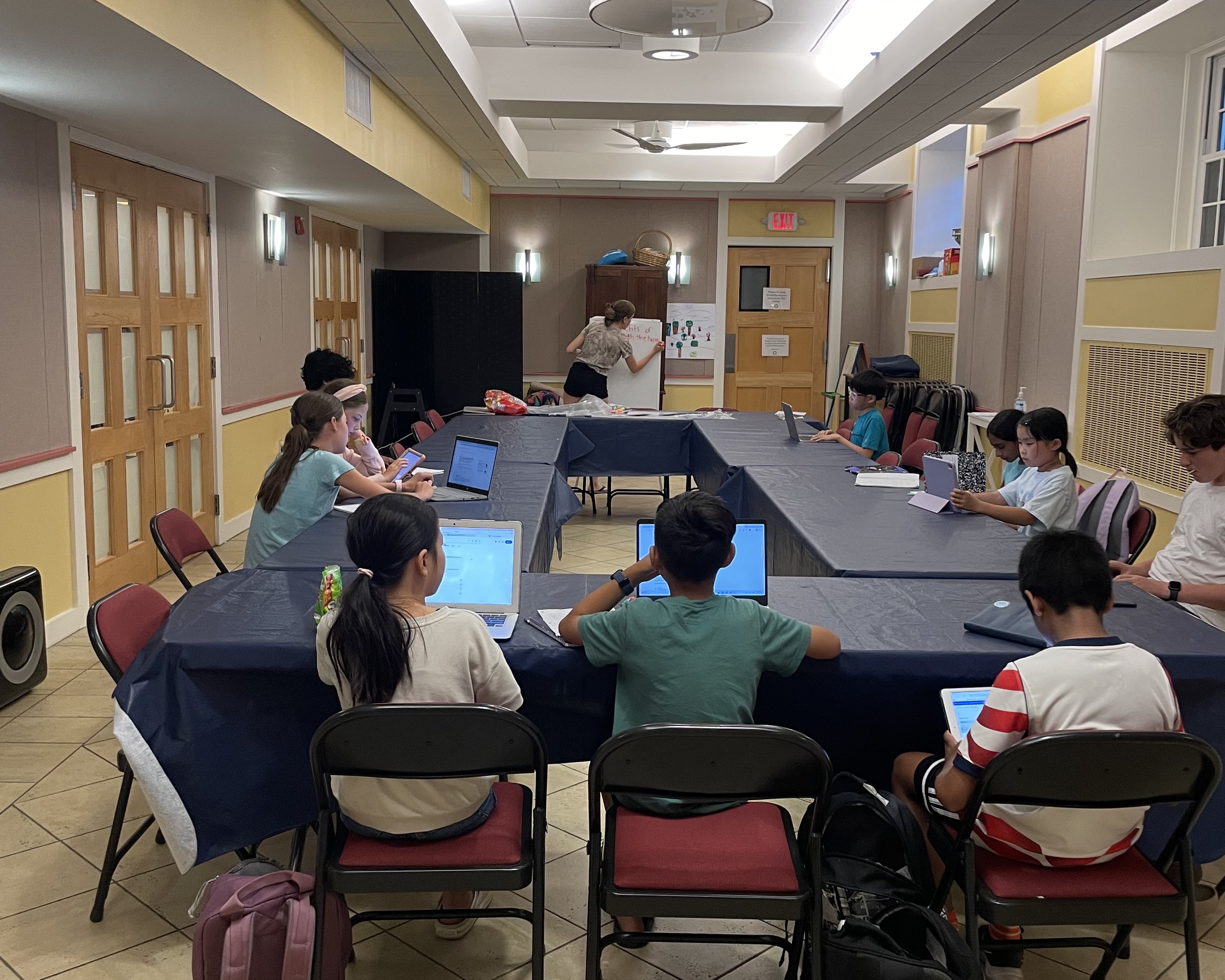 Students working on debate preparation around tables at camp